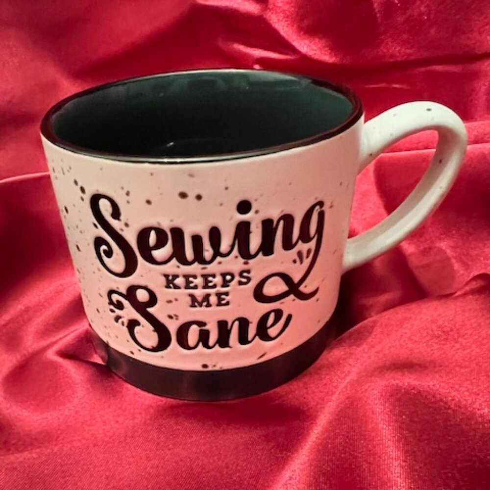 White‎ ceramic "Sewing Keeps Me Sane" coffee mug with a black rim and handle